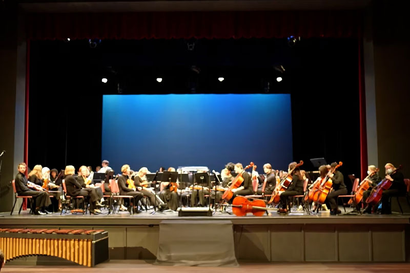 Philharmonic Orchestra playing instruments in Jones Auditorium.